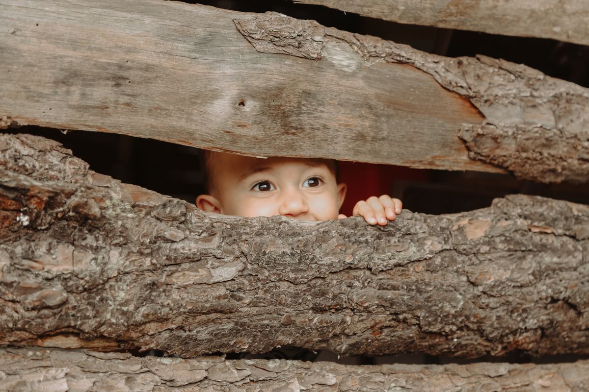Babygezichtje gluurt speels door houten planken