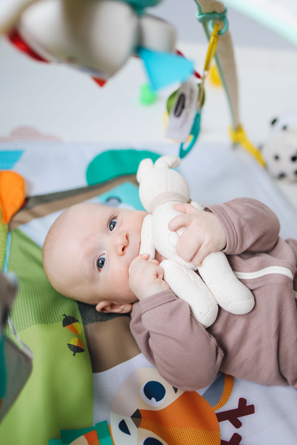 Baby speelt met een pluche speeltje in een kleurrijke kamer