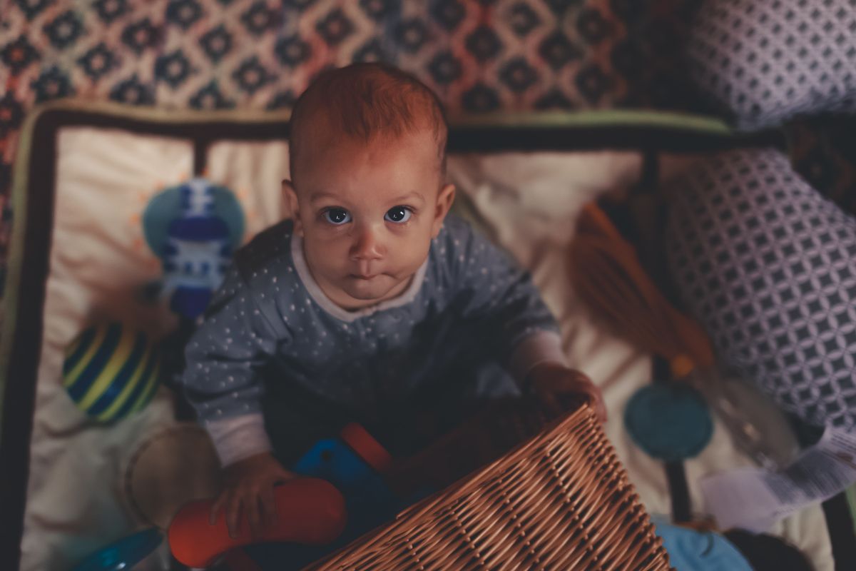 Baby in pyjama speelt met speelgoed uit een rieten mand