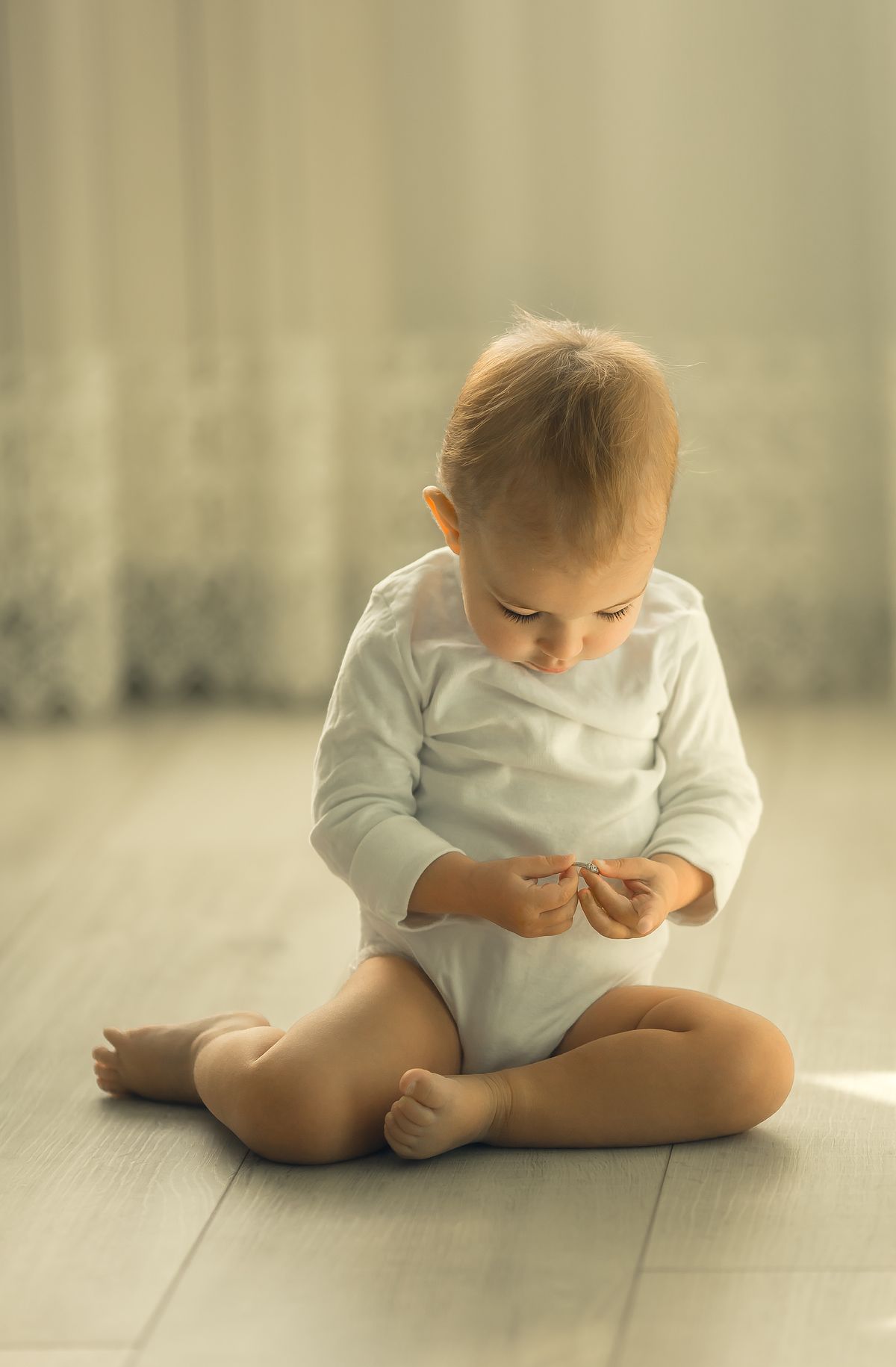 Baby zit op de vloer in een lichte kamer en kijkt nieuwsgierig rond