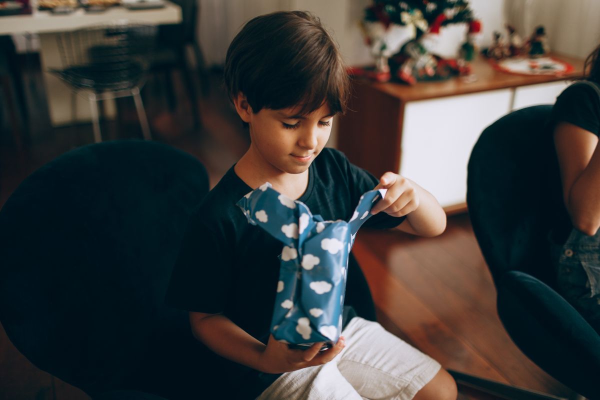 Vrolijk kind pakt een cadeau met blauw inpakpapier uit