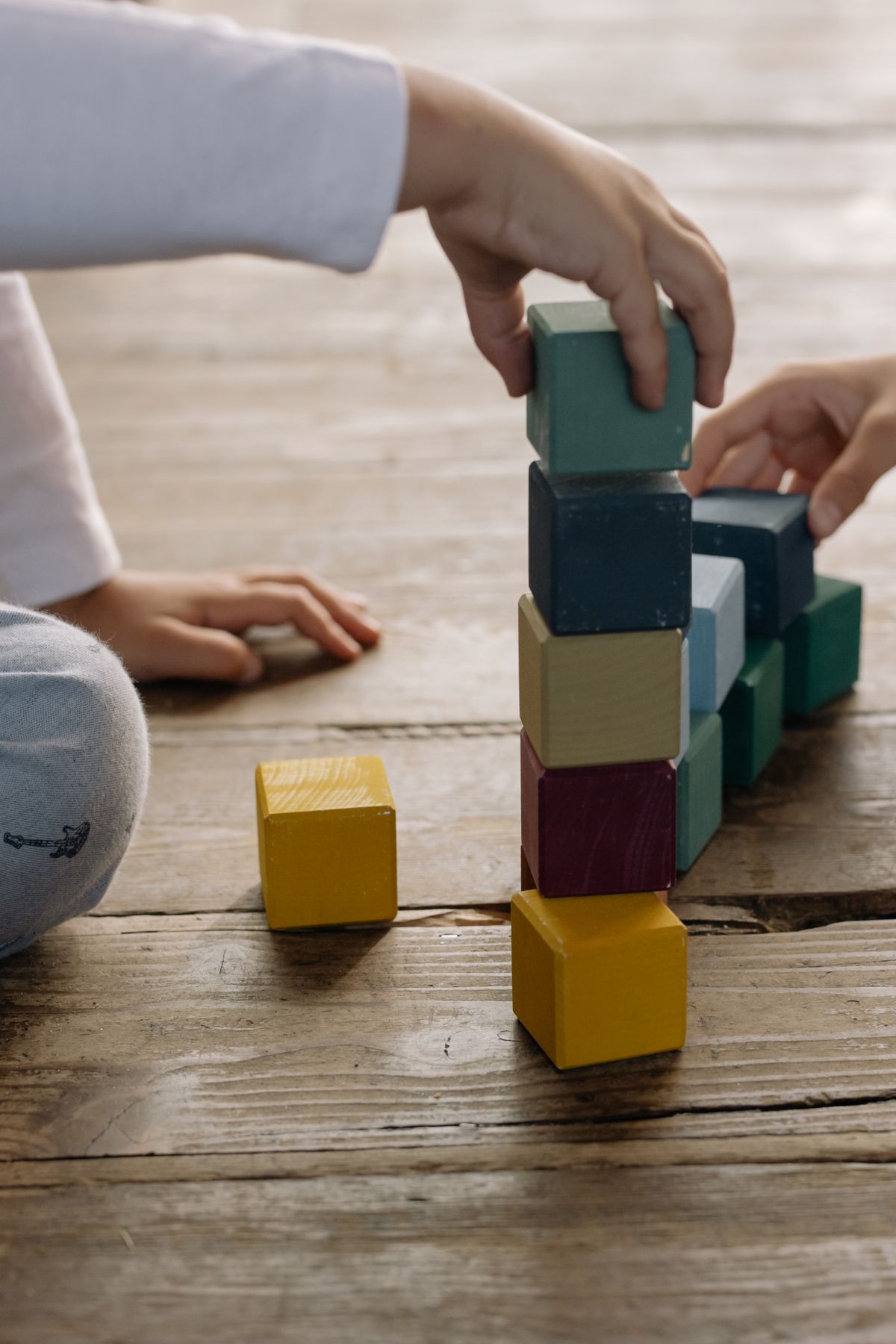 Kinderen bouwen een toren van kleurrijke houten blokken op de vloer