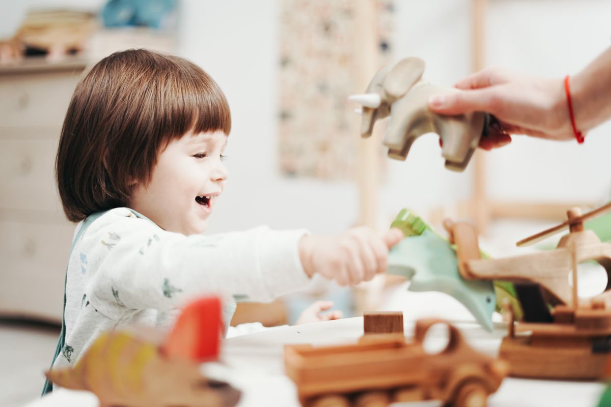 Lachend kind speelt met houten speelgoed in een lichte kamer