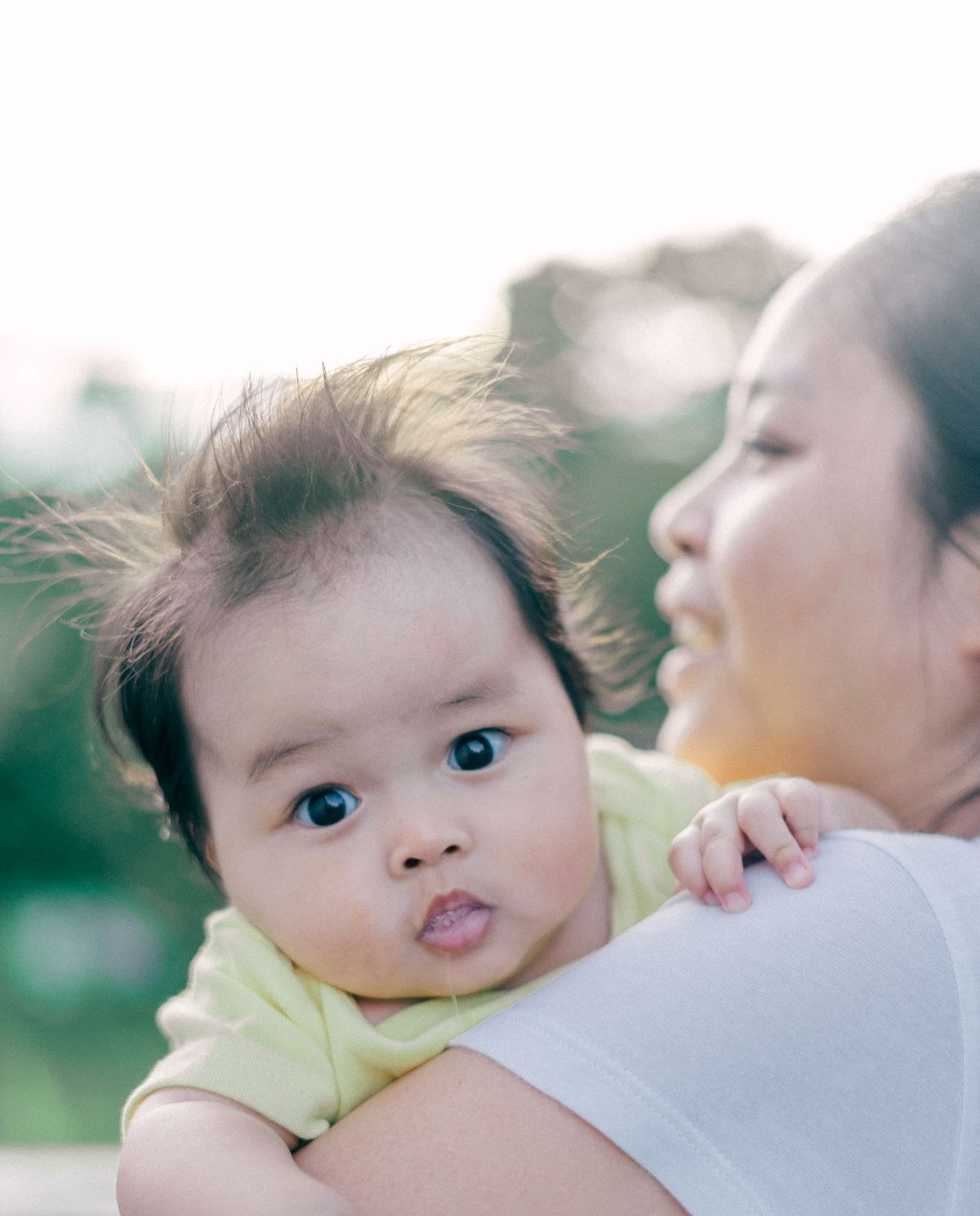 Lachende moeder houdt haar baby vast in een buitenomgeving