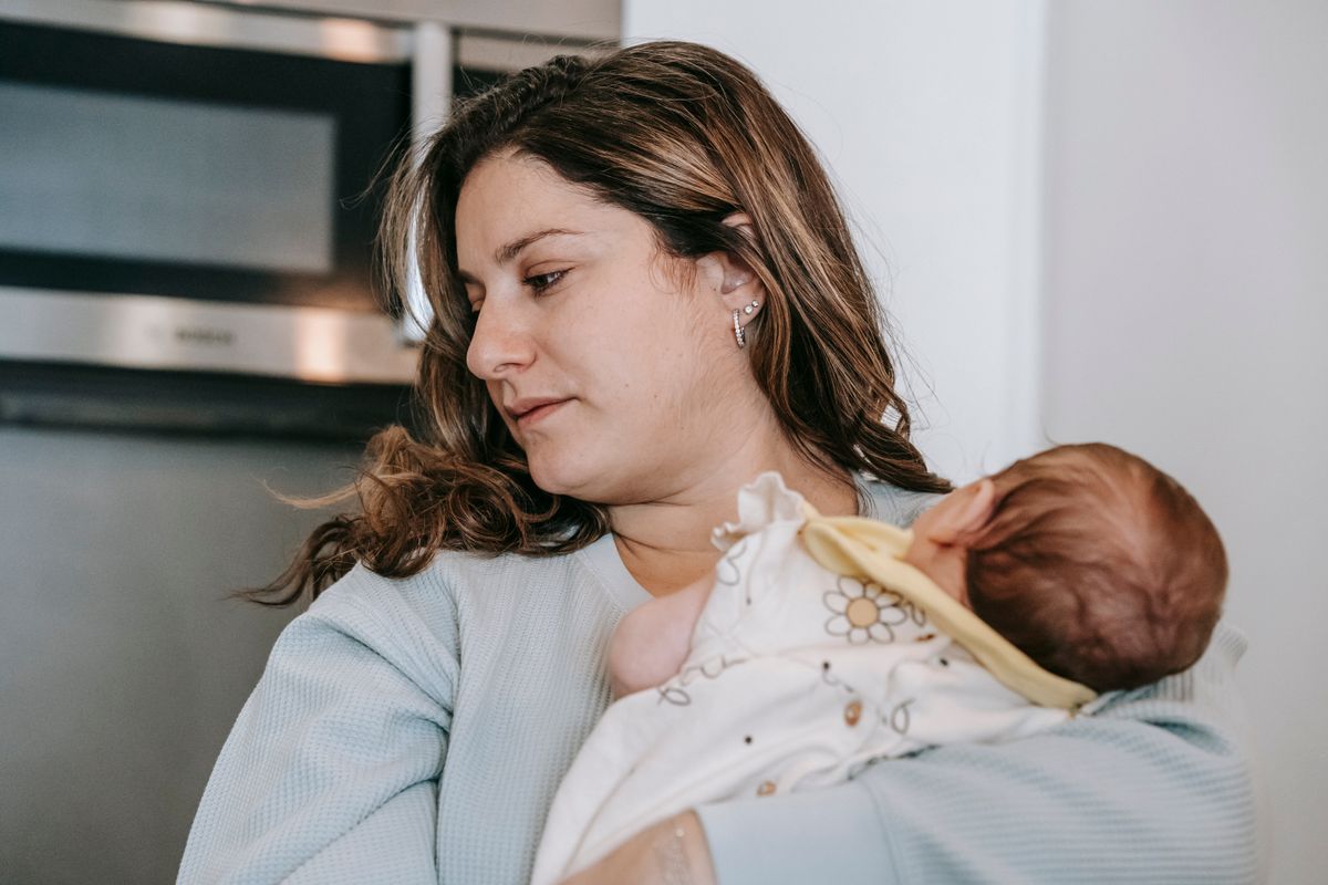 Moeder knuffelt haar pasgeboren baby in de keuken