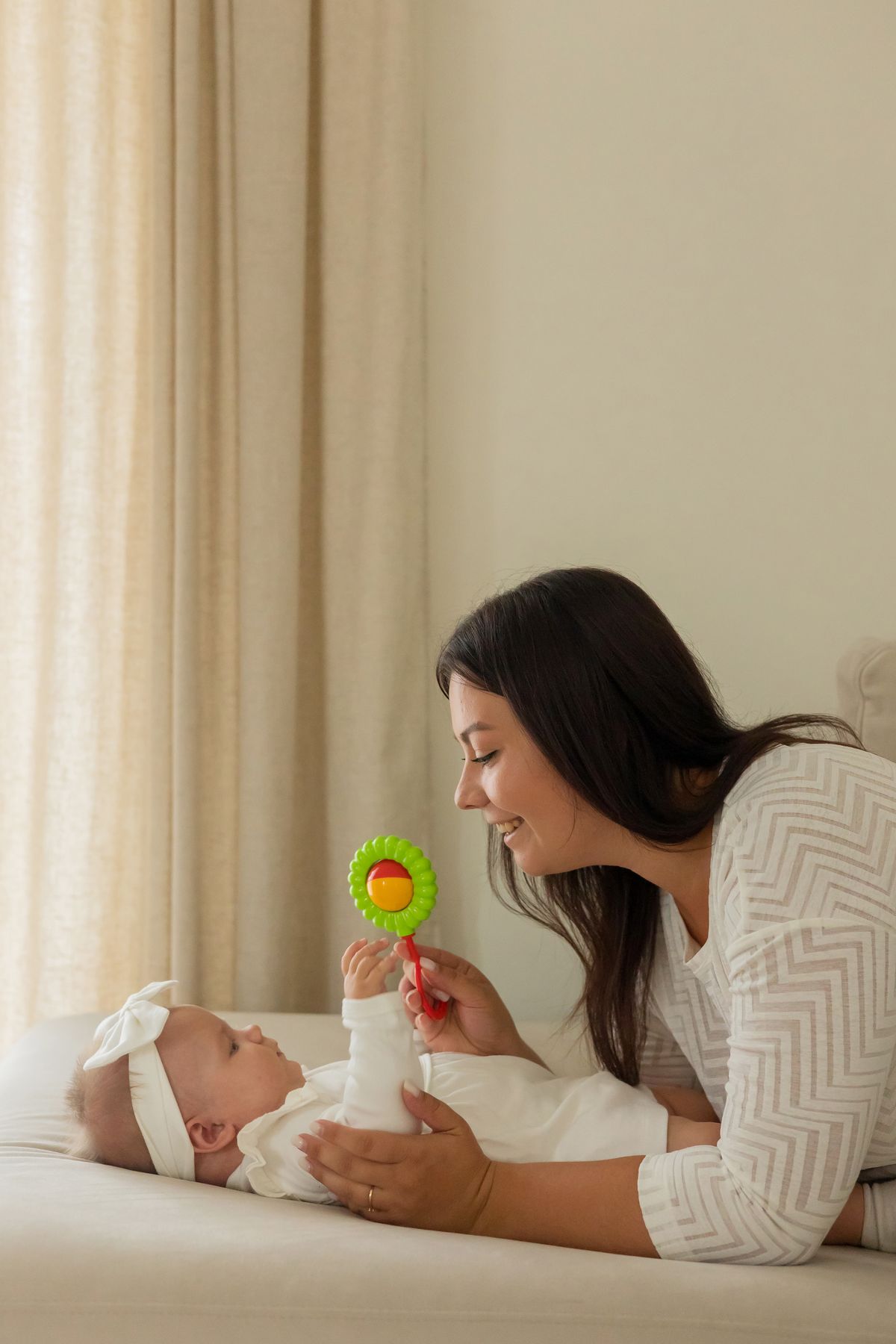 Vrolijke moeder speelt met haar baby met een kleurrijk speeltje