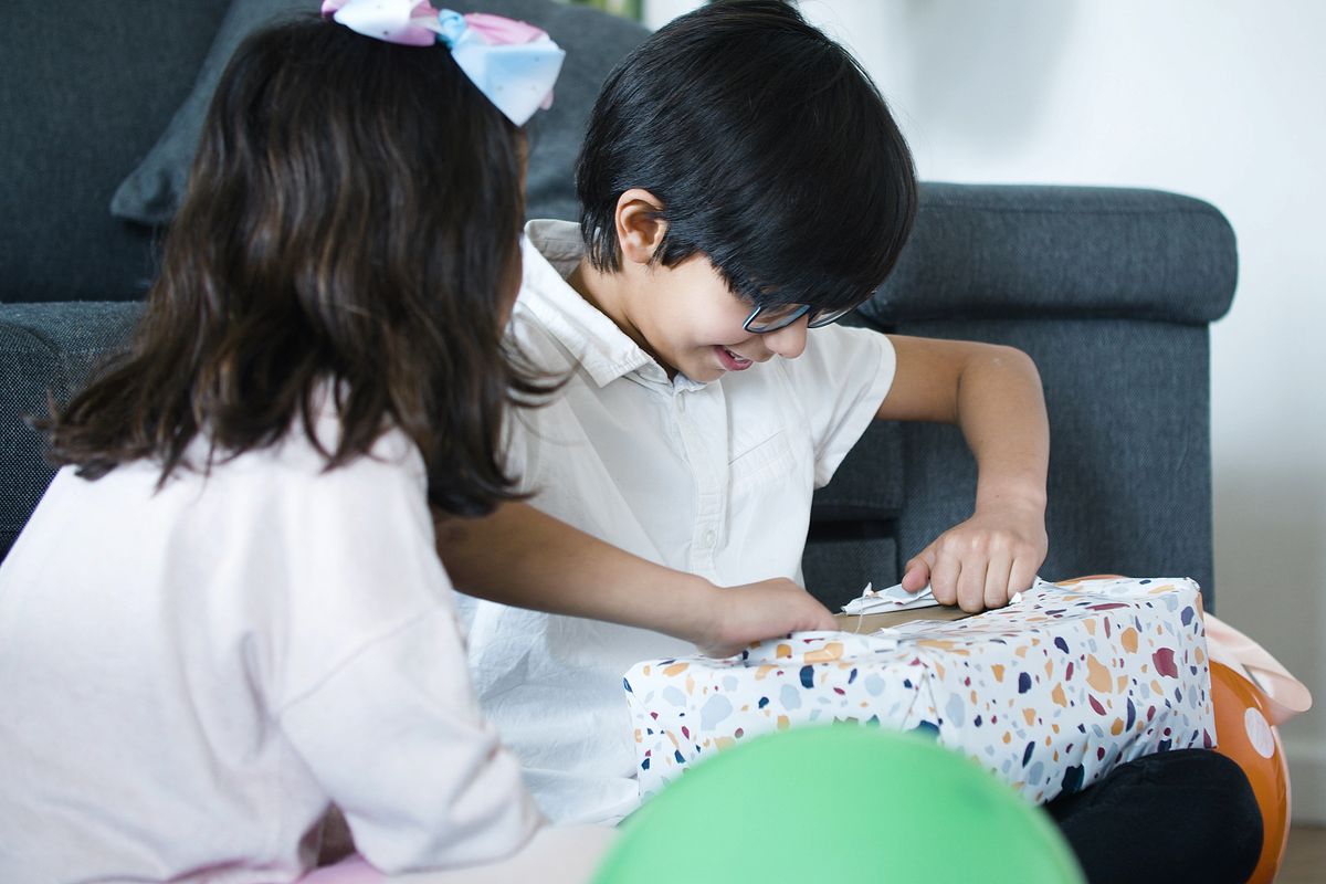 Twee blije kinderen pakken binnen samen cadeaus uit
